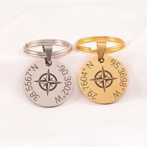 May include: Two compass keychains, one silver and one gold, with engraved coordinates and a compass rose.
