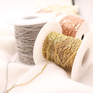 May include: Three spools of chain, one silver, one gold, and one rose gold. The spools are white plastic and the chain is delicate.