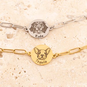 May include: Two silver and gold dog tag bracelets with engraved images of dogs and their names, "Koda" and "Tequila".