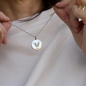 May include: A silver necklace with a round pendant featuring a dog's face and the name "Charlie" engraved on it.