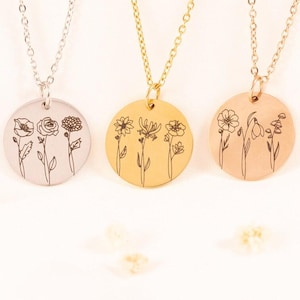 May include: Three circular pendant necklaces in silver, gold, and rose gold tones. Each round metal disc features a delicate black line art engraving of three distinct wildflowers. The pendants hang from matching thin metal link chains.