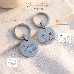 May include: Two silver-toned circular metal keychains with split rings. One keychain is engraved with the text Drive Safe, and the other features an engraved drawing of a family with the text You Are The Best, matching the provided handwritten notes.