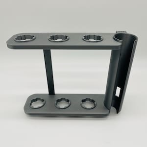 May include: A dark gray, multi-level stand with circular openings. The stand has a curved support on the right side and a rectangular base. The stand is designed to hold multiple items.