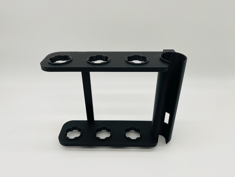 May include: A black 3D-printed stand with multiple circular openings and a cylindrical holder. The stand has a rectangular base with three openings and a top section with four openings. The design is modern and functional.