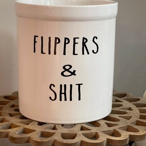 May include: White ceramic canister with black lettering that reads "Flippers & Shit".