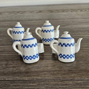 May include: Set of four white ceramic teapot napkin rings with blue and white checkered pattern.