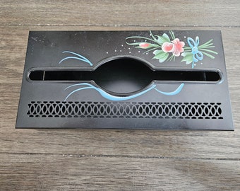 May include: Black metal tissue box holder with a blue and pink floral design. The holder has a decorative cutout pattern on the bottom.
