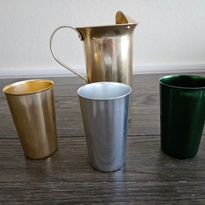 May include: A set of four aluminum cups, one gold, one silver, one green, and one larger gold pitcher.