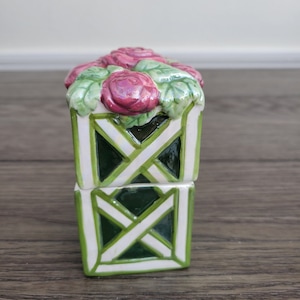 May include: A ceramic salt and pepper shaker set with a green and white lattice design and a pink rose flower design on top.