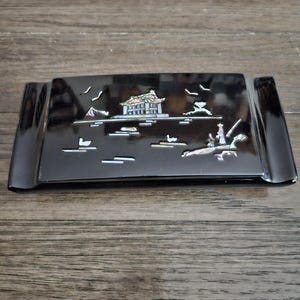 May include: A black lacquered tray with a mother-of-pearl inlay depicting a traditional Asian house and landscape.