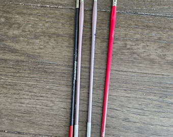 May include: Four paint brushes with red, black, and gray handles. The brushes have different sizes and shapes, including a fan brush.