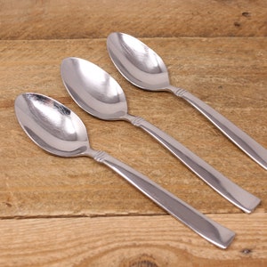 May include: Three silver spoons with rounded bowls and long, slender handles.