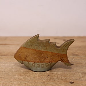 May include: A ceramic fish figurine with a blue and brown glaze. The fish has a stylised design with a curved body and a pointed tail.