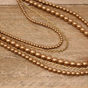 May include: A gold multi-strand necklace with large round beads.