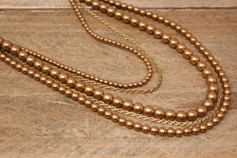 May include: A gold multi-strand necklace with large round beads.
