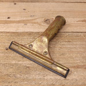May include: A brass window scraper with a black rubber blade. The scraper has a long handle with a hole in the top.