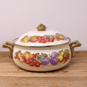 May include: Cream enamel pot with lid, decorated with a vibrant fruit pattern including cherries, plums, peaches, and strawberries. It has gold-coloured handles and a matching knob. A decorative kitchen item, perfect for cooking.