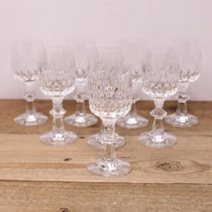 May include: Set of eight clear glass wine glasses with a cut crystal design. The glasses have a round bowl and a tall stem.