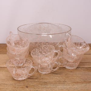 May include: A vintage glass punch bowl and cups set with a crackle finish. The bowl and cups are clear glass with a delicate pink crackle pattern.