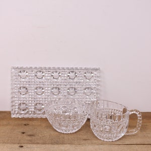 May include: A set of three clear glass bowls with a geometric pattern. The bowls are on a wooden surface.