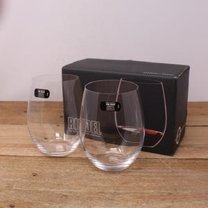 May include: Two clear glass wine glasses with a Riedel logo on the box. The glasses are designed for Cabernet and Merlot wines.