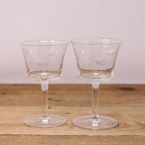 May include: Two clear glass stemmed wine glasses with an etched thistle design.