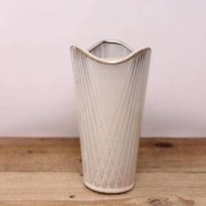 May include: White ceramic vase with a geometric pattern. The vase has a wide mouth and a narrow base.