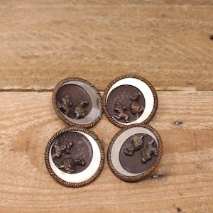 May include: Four silver and brown metal buttons featuring a design of people running around a crescent moon.