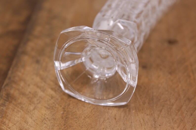 May include: A clear glass vase with a textured, geometric pattern. The vase has a wide, circular base.