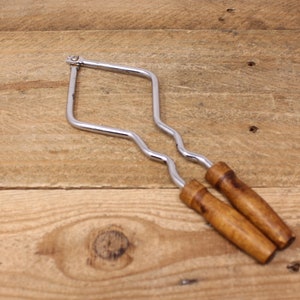 May include: A pair of chrome nutcrackers with wooden handles. The nutcrackers are in the shape of a diamond and have a wavy design.