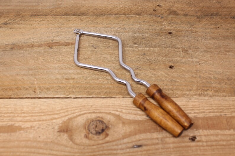 May include: A pair of chrome nutcrackers with wooden handles. The nutcrackers are in the shape of a diamond and have a wavy design.