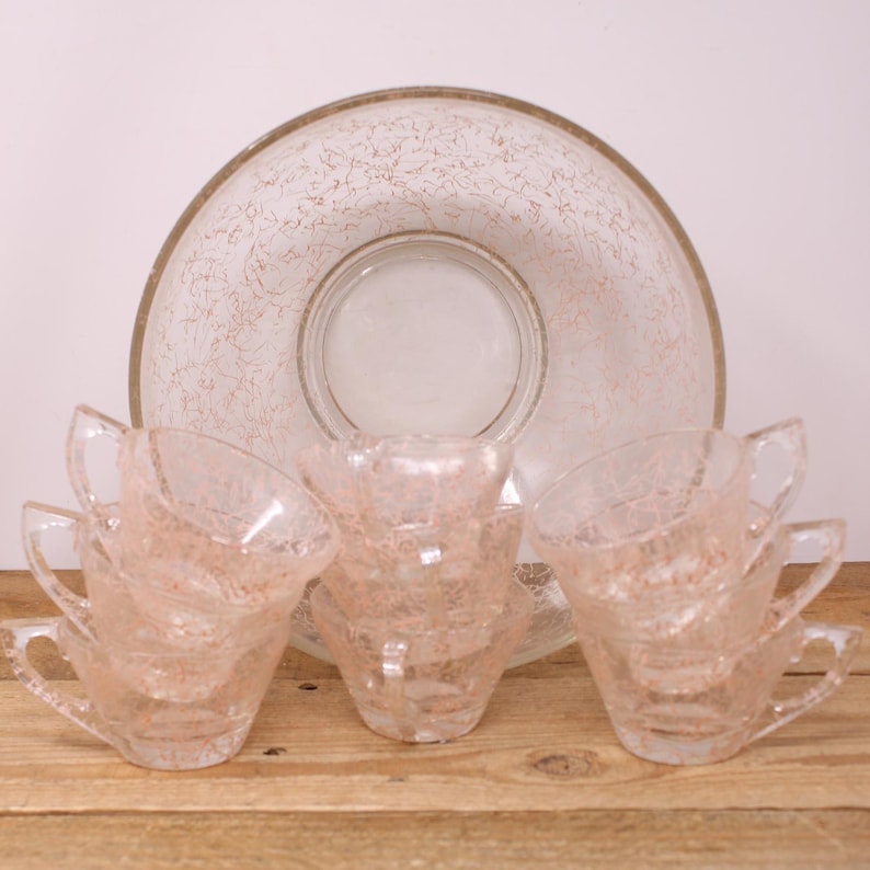 May include: A vintage glass punch bowl and cups set with a pink swirl design. The bowl has a clear glass base and a pink swirl design throughout. The cups are also clear glass with a pink swirl design. The set is perfect for entertaining.