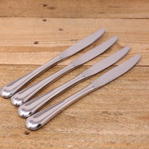 May include: Four silver dinner knives with rounded handles.