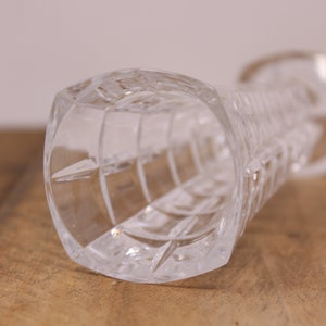 May include: A clear glass vase with a cut glass design. The vase is empty and has a round opening at the top.