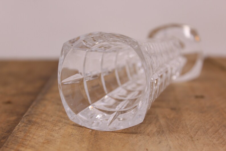 May include: A clear glass vase with a cut glass design. The vase is empty and has a round opening at the top.