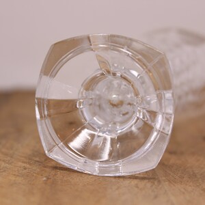 May include: The bottom of a clear glass goblet with a wide, flat base and a textured design.