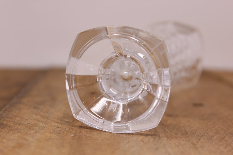 May include: The bottom of a clear glass goblet with a wide, flat base and a textured design.