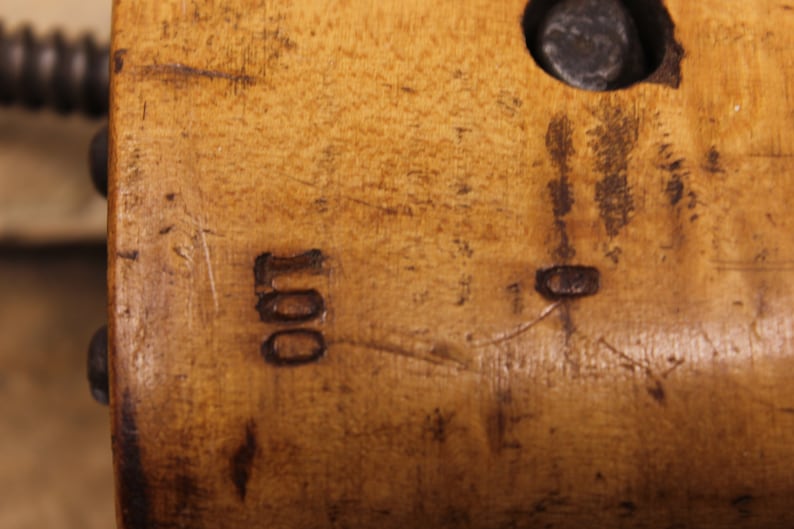 May include: Close-up of a wooden surface with the number "100" carved into it. The surface is a light brown color and has a few scratches.