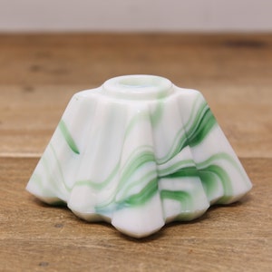 May include: A white and green swirl glass candle holder with a star-shaped base.
