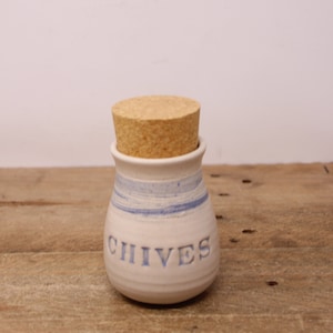 May include: White ceramic jar with a blue stripe design and a cork lid. The jar is labeled "CHIVES".