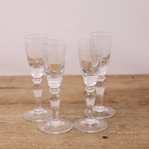 Peut inclure: Quatre verres à shot en verre transparent avec un motif gravé décoratif sur la moitié inférieure du verre. Les verres ont une tige haute et fine et une base ronde.