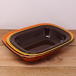 May include: A set of three nesting rectangular baking dishes with orange, yellow and brown enamel finishes.