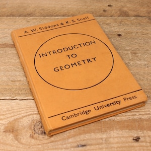 May include: A vintage book titled "Introduction to Geometry" by A.W. Siddons & K.S. Snell. The book has a tan cover with black text inside a black circle. The book is from Cambridge University Press.