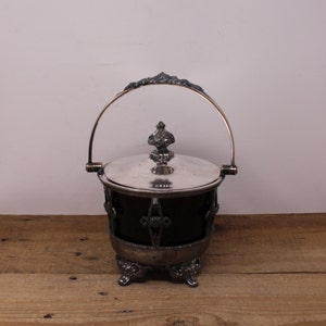 May include: Silver plated sugar bowl with a glass liner and a handle. The bowl has a decorative design and sits on four feet.