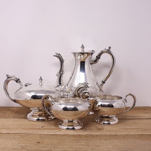 May include: A silver tea set comprising a teapot, sugar bowl and creamer. The set features an ornate design and is in excellent condition.