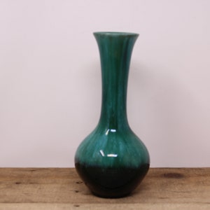 May include: A tall, elegant vase with a glossy finish. The ceramic vase transitions from a deep teal at the base to a lighter teal at the top. The vase has a rounded base and a slender, elongated neck.