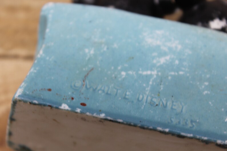 May include: Close-up of a blue ceramic figurine with the text "&copy; WALT DISNEY" and "5185" on the bottom.