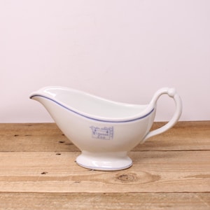 May include: A white ceramic mug with a black handle and the text "But First, Coffee" in a bold, black font. The mug is set against a blurred background, suggesting a cozy setting.