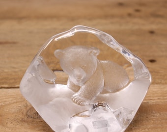 May include: A clear glass sculpture of a baby bear cub inside a cave-like shape.