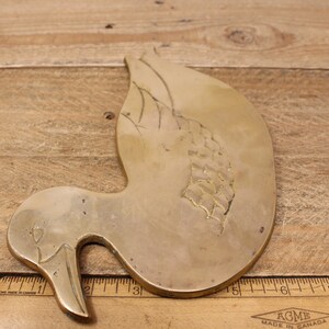 Pode incluir: Uma decora&ccedil;&atilde;o de parede de pato de lat&atilde;o com um design gravado detalhado. O pato est&aacute; em uma pose de voo com a cabe&ccedil;a virada para o lado. O pato mede aproximadamente 18 cm de comprimento.